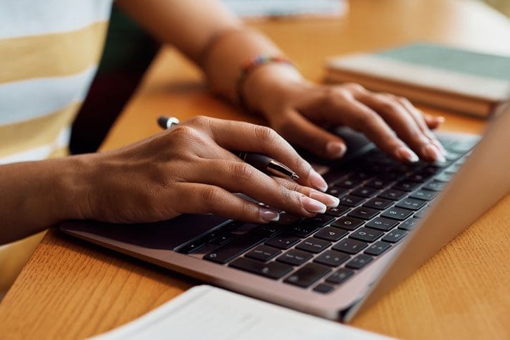 A closeup of a pair of hands typing on a laptop keyboard