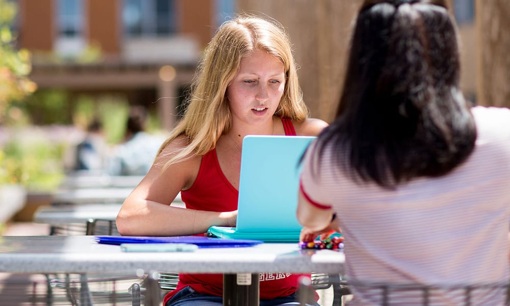 A UW student works at an outside table on East Campus Mall during Summer Term.
