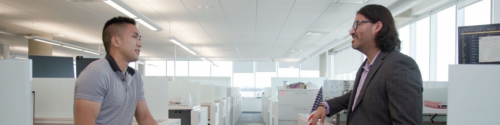 Manny Avila having a conversation with a coworker in the office.