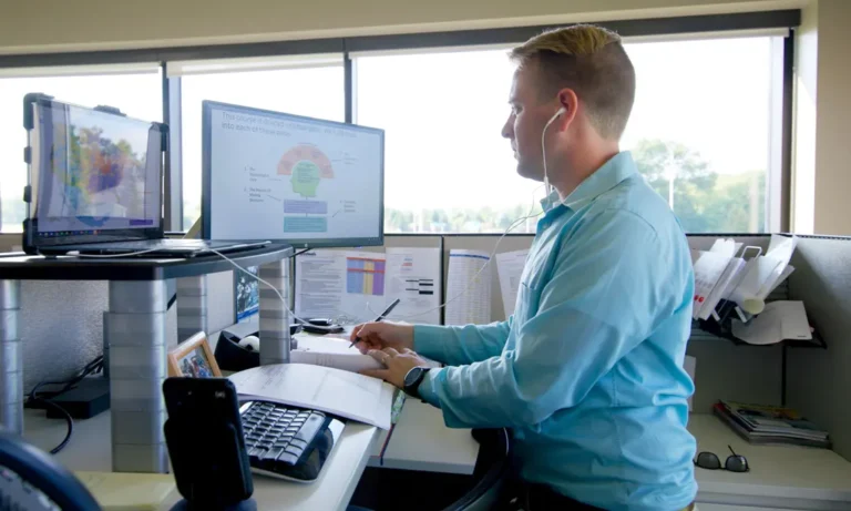 John sitting at his computer in front of a large window