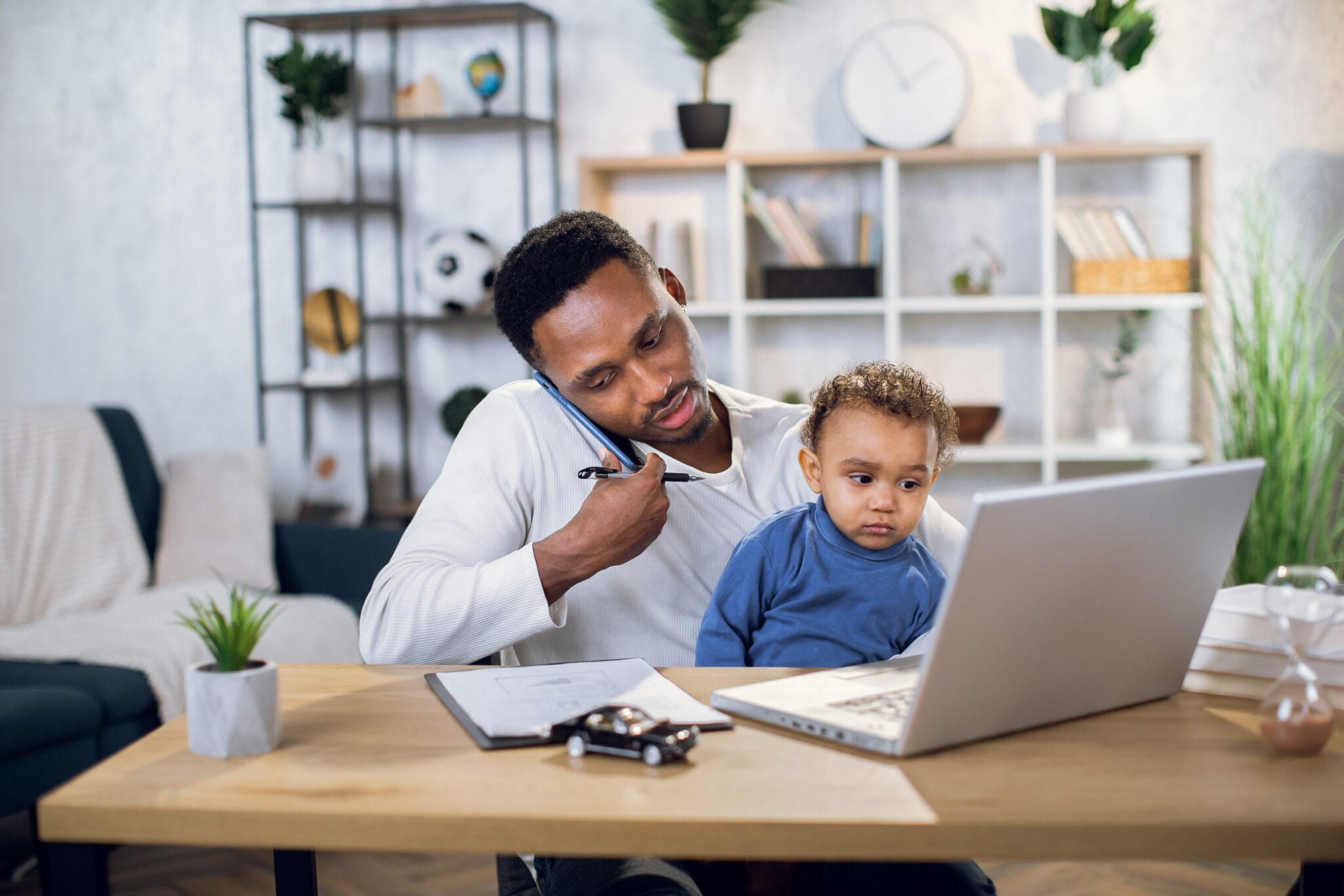 A man with his child on his lap speaking on the phone.