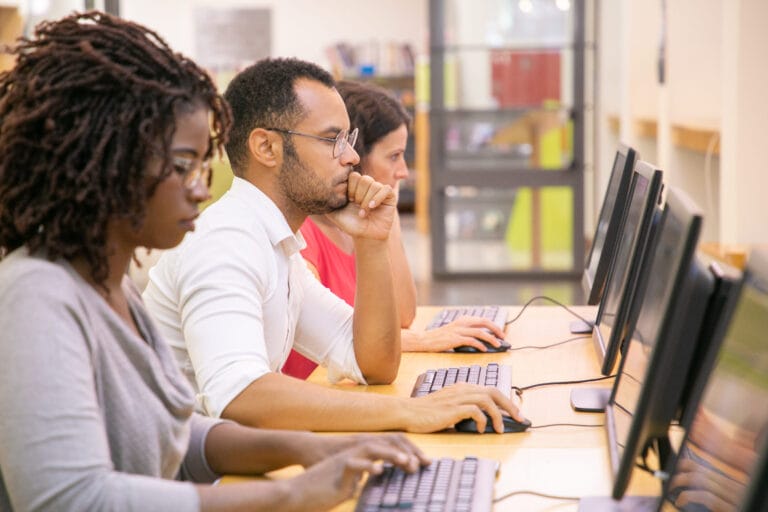 A trio of students in a computer lab working.