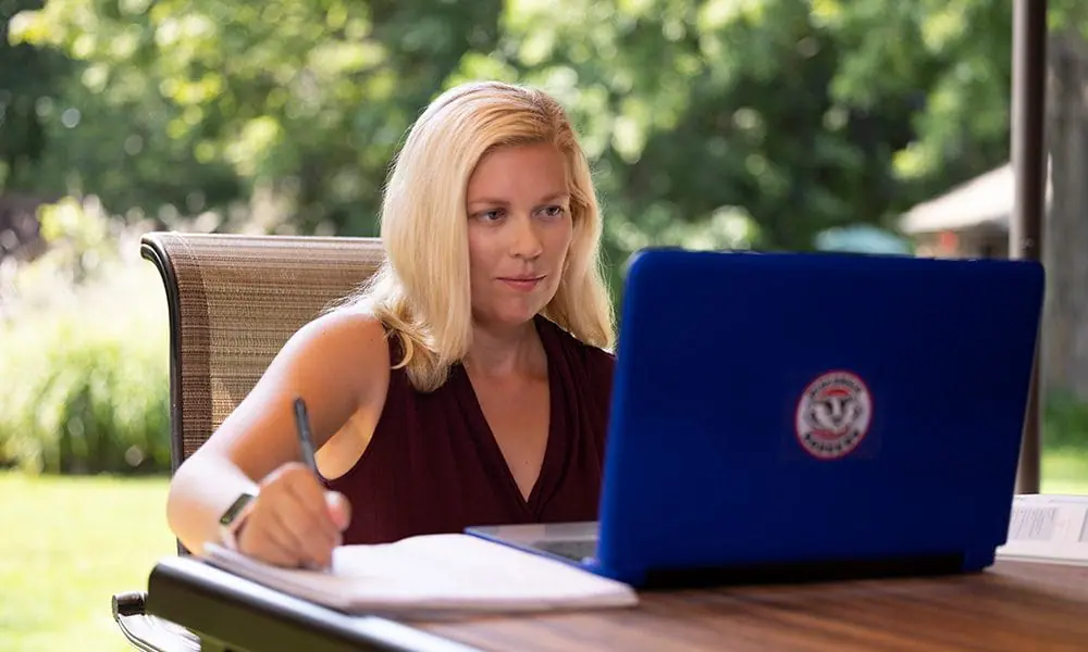 Kristy at her computer outside on a sunny day