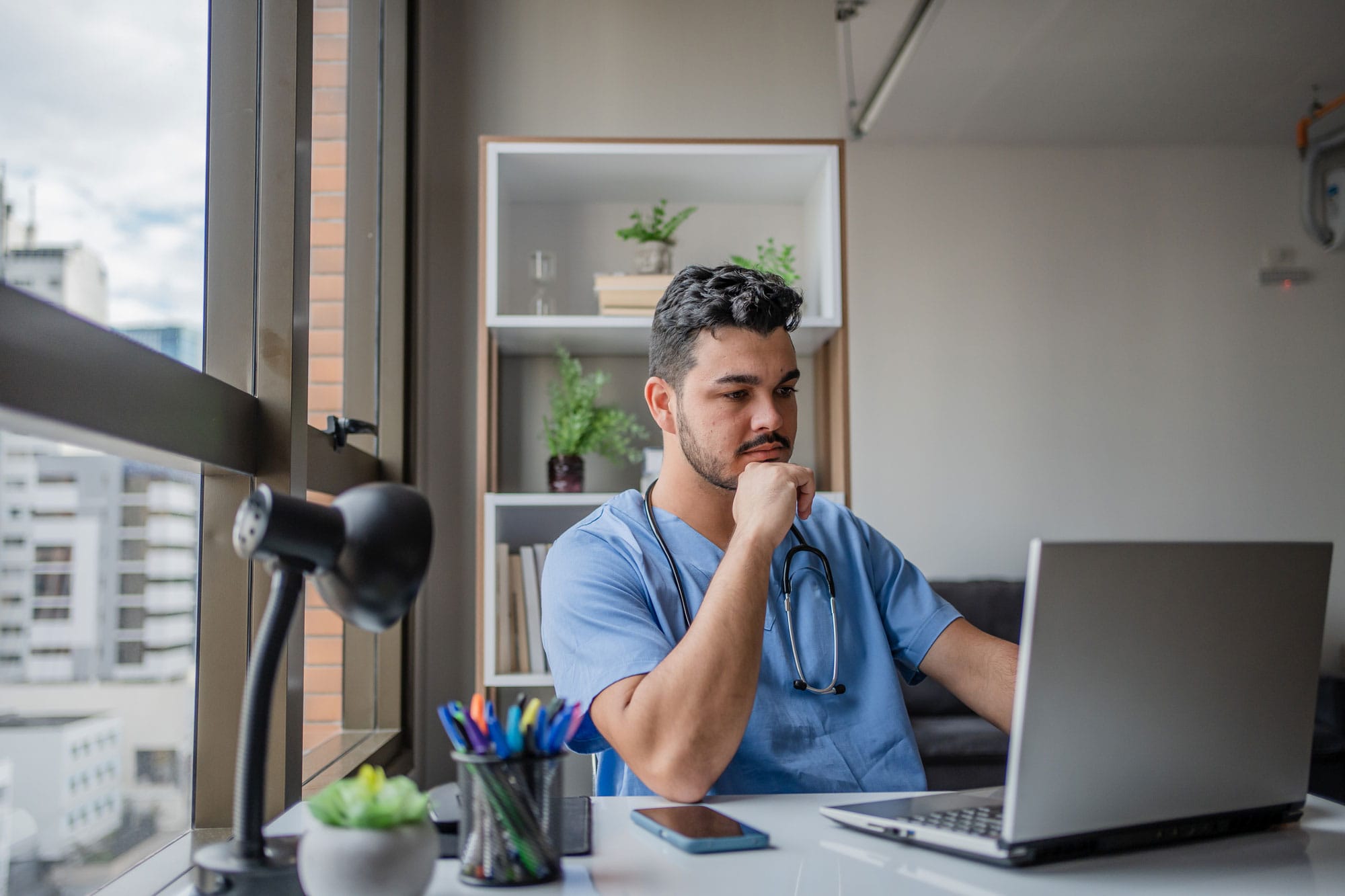 Male nurse working on laptop at home.