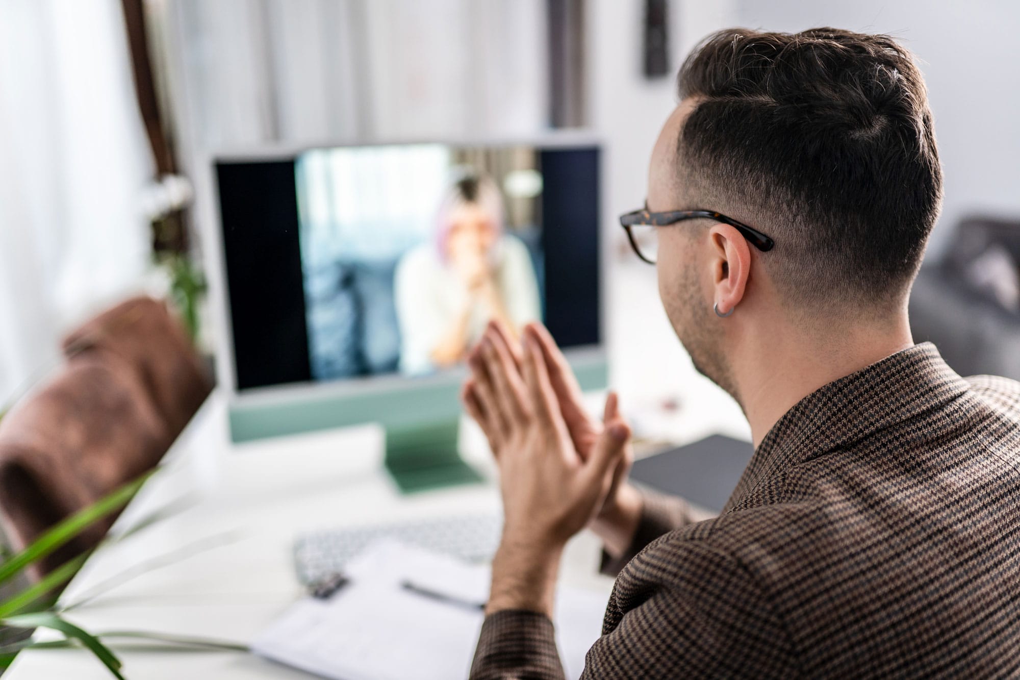 A man sitting at his desk attending a virtual conference from his computer